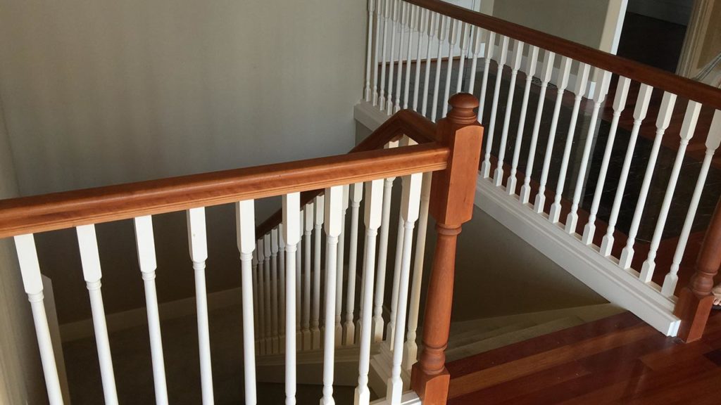 Wooden staircase railing with white balusters