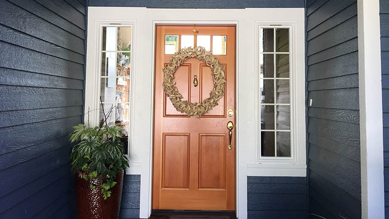 Wooden front door with wreath and plant
