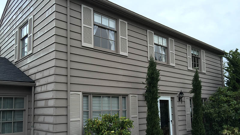 Beige two-story house exterior with shrubs