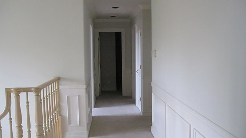 Empty white hallway with wooden railing