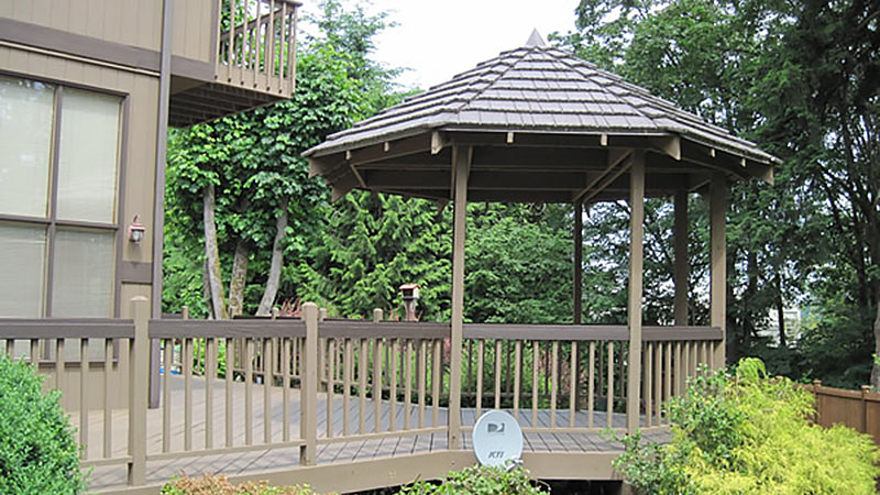 Backyard wooden gazebo on deck with railing