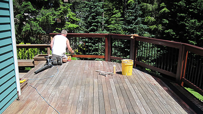 Person repairing wooden deck with tools