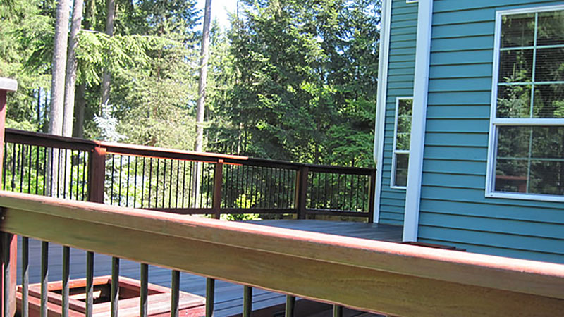 Blue house deck with wooden railing and trees
