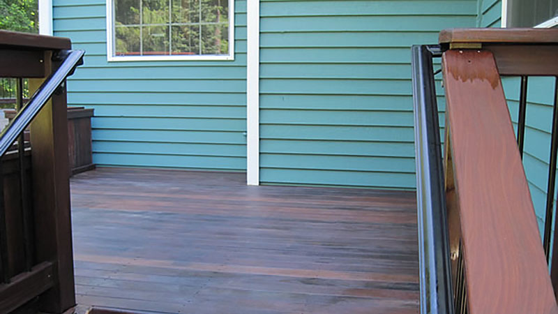 Empty wooden deck with teal house siding