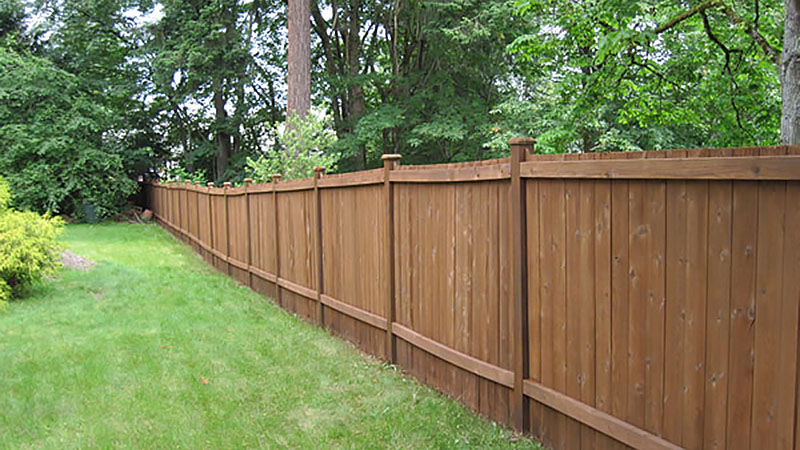 Long wooden privacy fence along green backyard