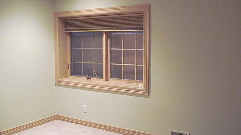 Empty beige room with window and wooden trim
