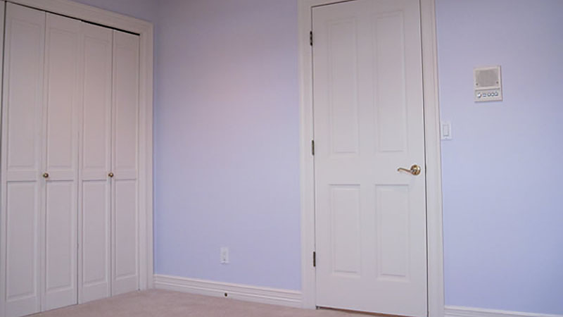 Empty lavender room with white door and closet