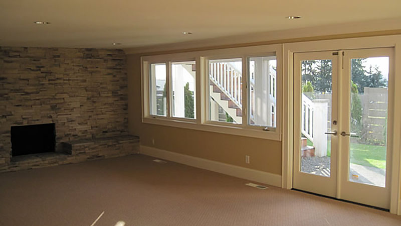 Bright basement living room with stone fireplace