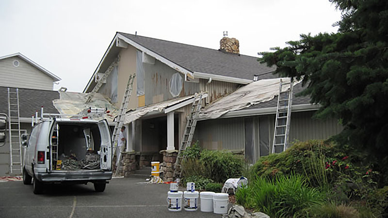 House exterior renovation with ladders and van