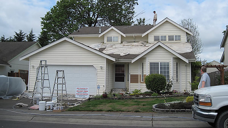 Workers repairing roof of suburban house