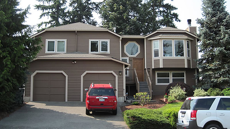 Two-story brown house with red SUV