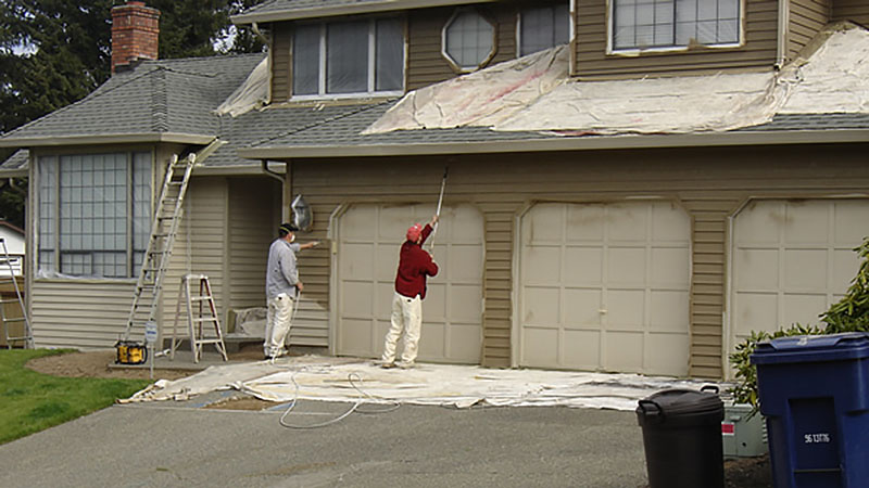 Two painters painting garage doors