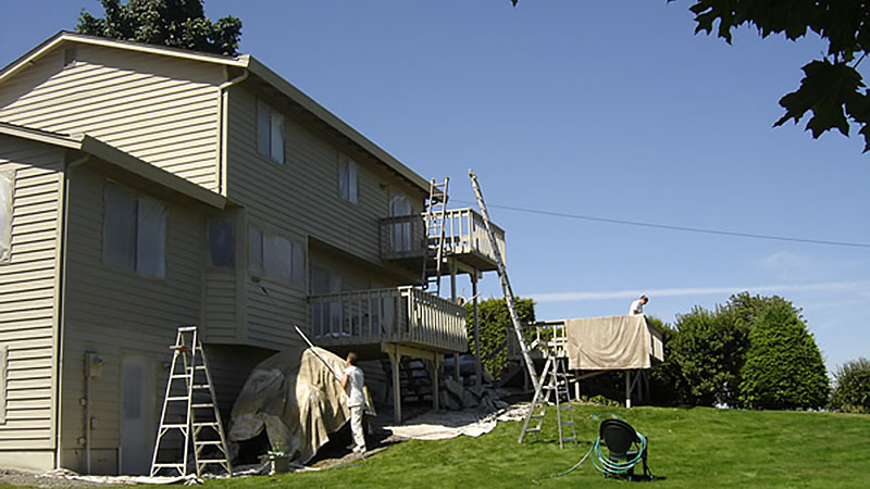 Painters repainting two-story house exterior