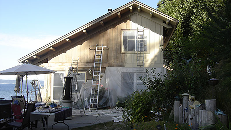 House exterior painting with ladders by waterfront