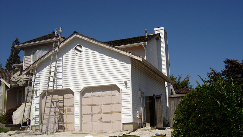 White house with ladders leaning on roof