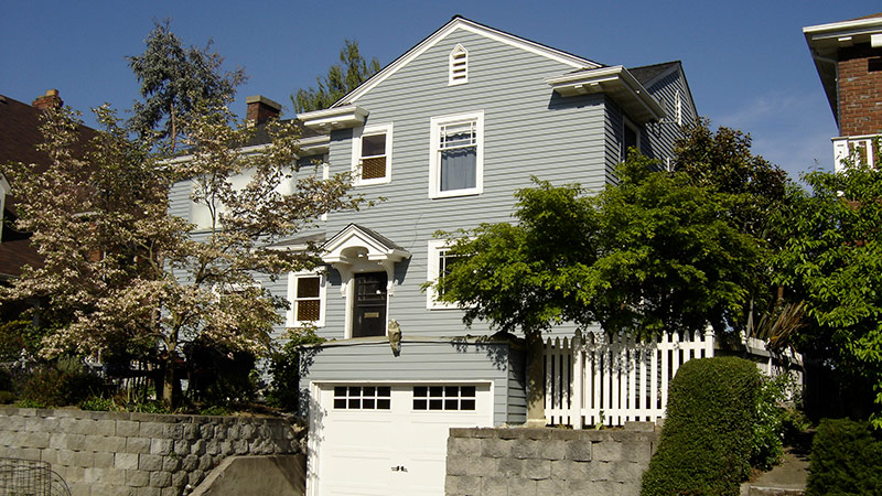 Gray two-story house with white picket fence