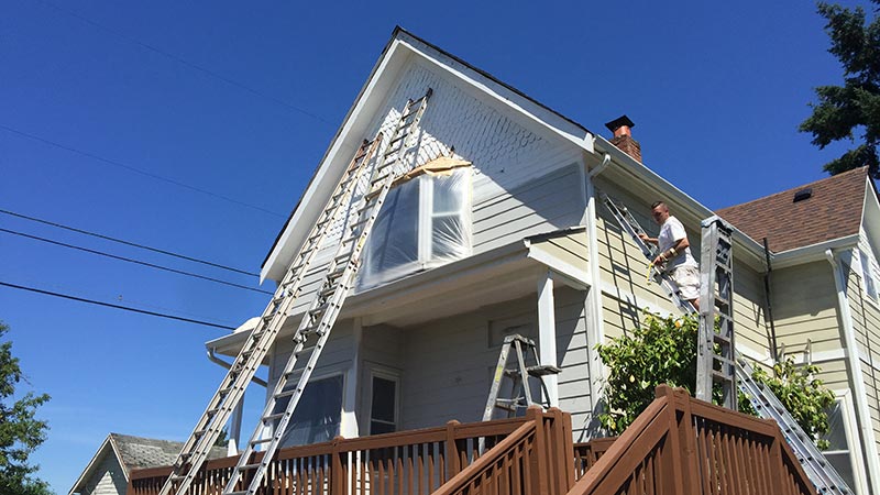 Workers painting two-story house exterior