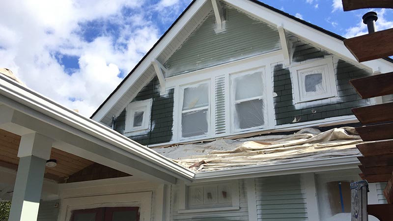 Gabled house undergoing exterior painting