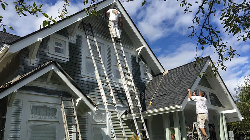 Painters on ladders painting house exterior
