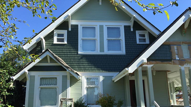 Green Craftsman-style house with white trim