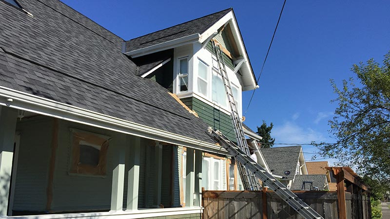 Roofing ladders on green two-story house