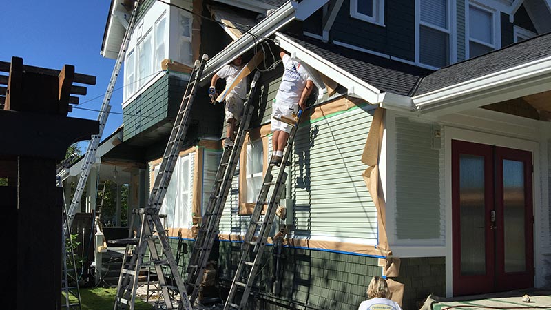 Painters on ladders repainting house exterior