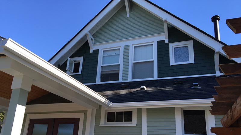 Green craftsman style house with white trim