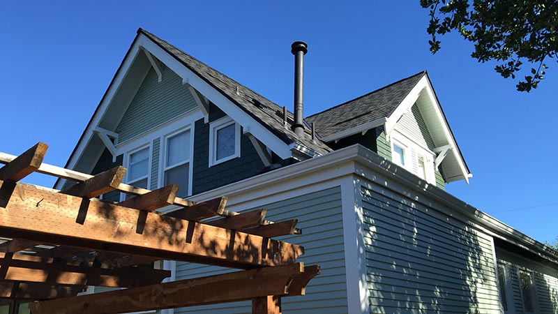 Green Craftsman house with wooden pergola