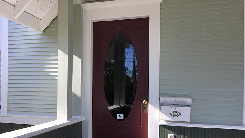 Maroon door with oval glass and mailbox