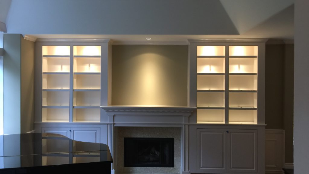 Illuminated built-in shelves flanking fireplace