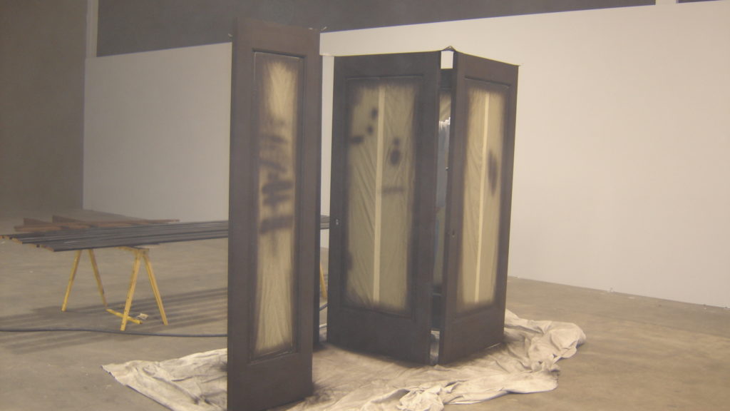 Painted doors drying on drop cloth in workshop